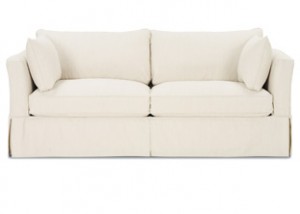 A white couch with two pillows on top of it.