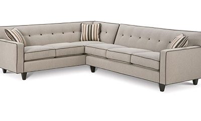 A sectional sofa with two pillows and three legs.