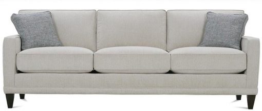 A white couch with three pillows on it