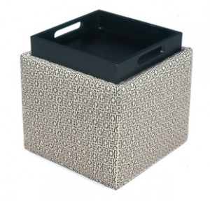 A square ottoman with a tray on top of it.