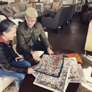 Two people sitting on a couch looking at puzzles.