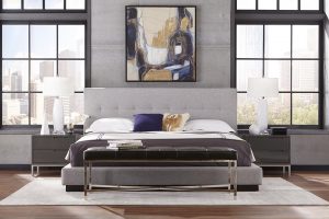 A bed with grey headboard and white sheets