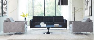 A black couch in front of a window with a coffee table.